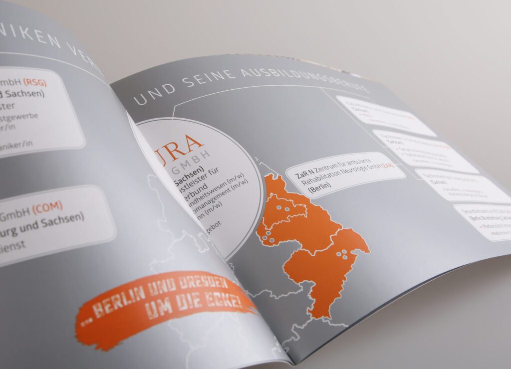 Hochwertige Broschüre mit silberner Druckveredelung, geöffnete Doppelseite mit Infografik, Karte und glänzender Metallic-Optik für eine edle Präsentation
