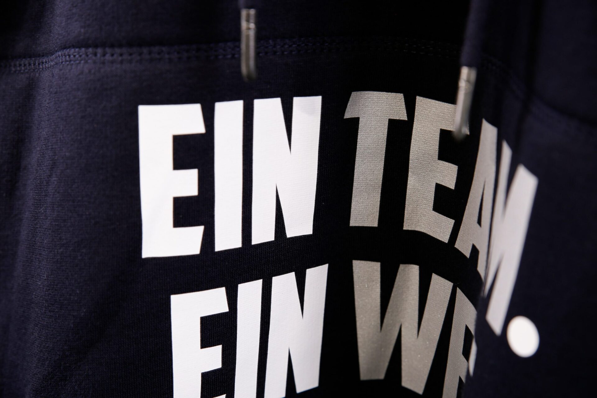 Detailansicht von weißer gedruckter Schrift auf dunkelblauem Pullover