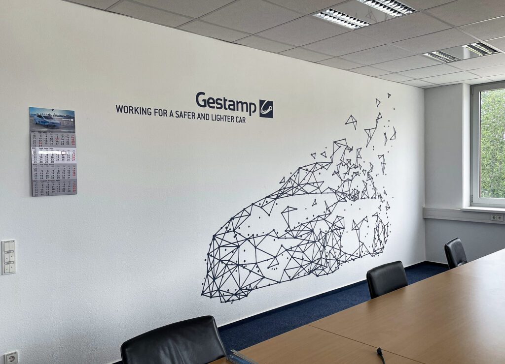 Wandgestaltung mit Firmenlogo und geometrischem Autodesign bei Gestamp im Konferenzraum