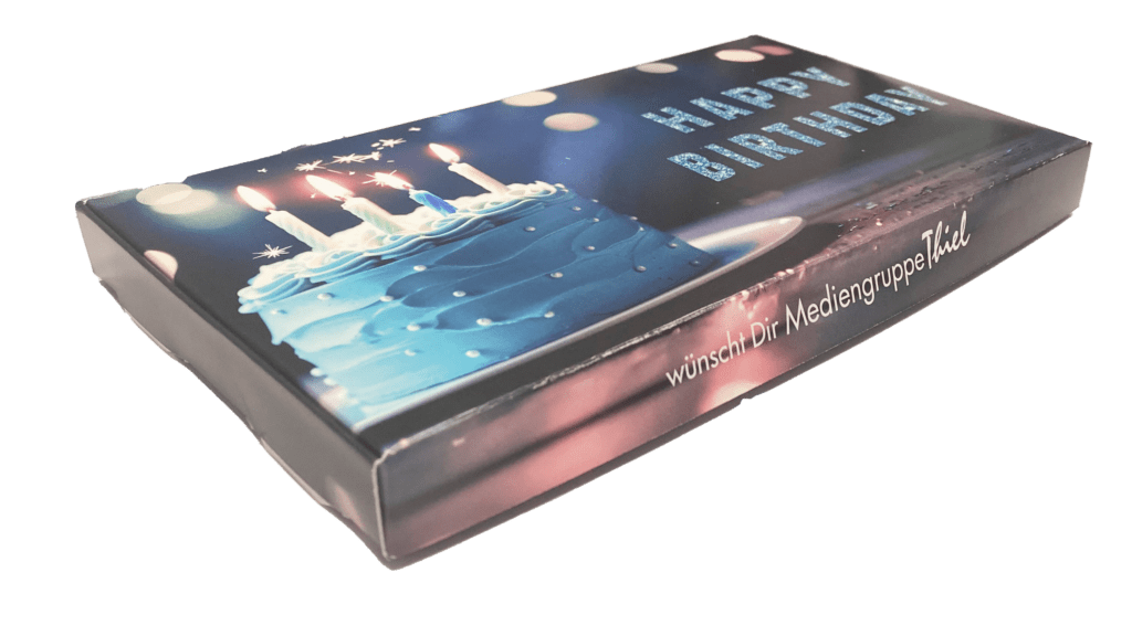 Edle Geburtstags-Geschenkbox im Corporate Design der Mediengruppe Thiel mit Happy Birthday Motiv und blauem Geburtstagskuchen.