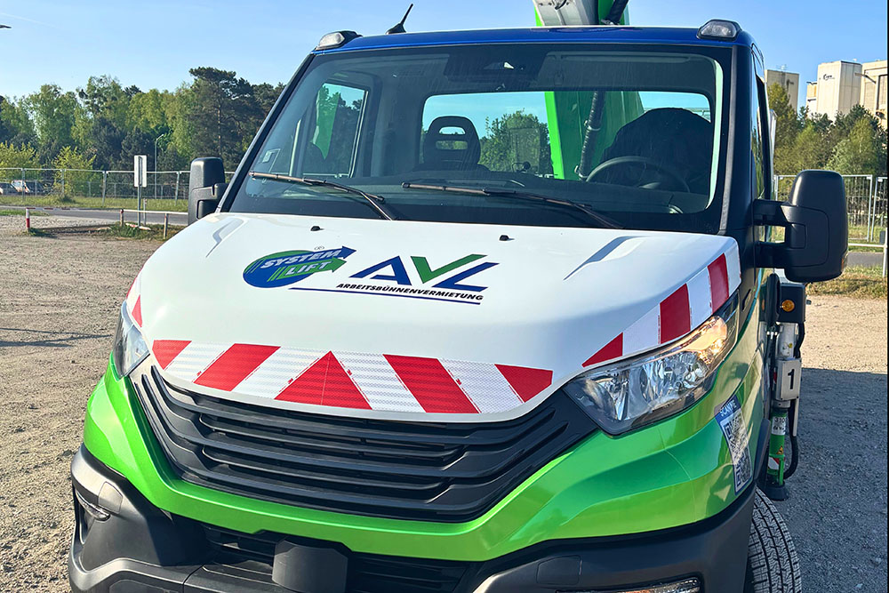 Teilfolierung_LKW_Arbeitsbühne_Front_AVL2_web Frontalansicht eines AVL-Arbeitsbühnenfahrzeugs mit SYSTEM LIFT-Logo und roten Warnmarkierungen auf der Motorhaube.