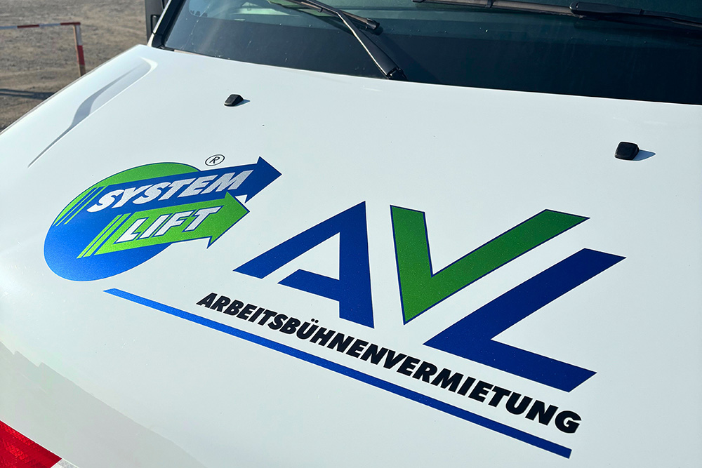 Teilfolierung_LKW_Arbeitsbühne_Front_AVL3_web Nahaufnahme der Motorhaube eines Fahrzeugs mit den Logos von SYSTEM LIFT und AVL Arbeitsbühnenvermietung