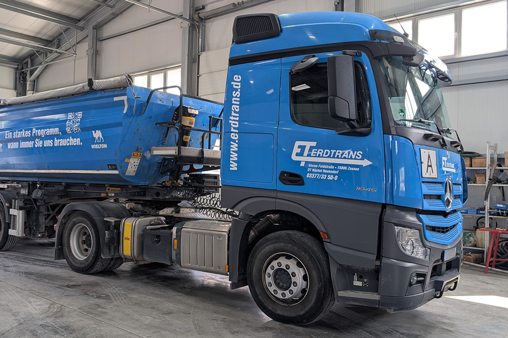 Fahrzeugbeschriftung Erdtrans mit Claim Seitliche Ansicht eines Erdtrans-LKWs mit auffälliger Folierung und Claim, gestaltet von der Mediengruppe Thiel in Corporate Design.