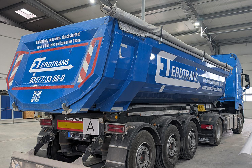 Heckansicht eines blau folierten Kippaufliegers der Firma Erdtrans mit Recruiting-Aufdruck, gestaltet von der Mediengruppe Thiel. Heckansicht eines blau folierten Kippaufliegers der Firma Erdtrans mit Recruiting-Aufdruck, gestaltet von der Mediengruppe Thiel.