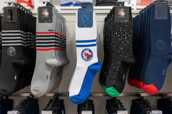 Socken-Display im Laden: Paar mit blau-weißen Streifen und Turbine-Potsdam-Logo, befestigt am grauen Sattelreiter, Größenangabe oben.