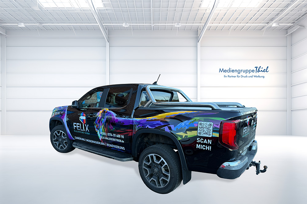 Schwarzer Pickup mit bunter Fahrzeugbeschriftung eines Malerbetriebs in heller Halle der Mediengruppe Thiel.