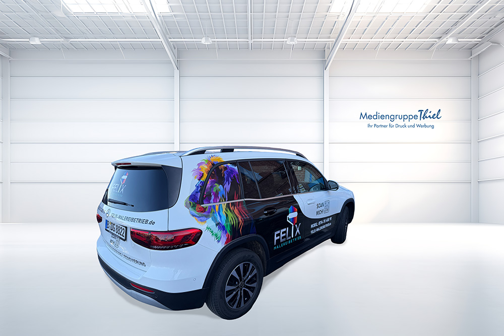 Gebrandeter SUV des FELIX Malerbetriebs mit buntem Löwenmotiv und Beschriftung in heller Halle der Mediengruppe Thiel, schräg von hinten fotografiert.