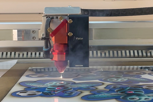 CO₂-Laser mit Vision-Kamera schneidet UV-bedruckte Untersetzer passgenau aus einer Platte.