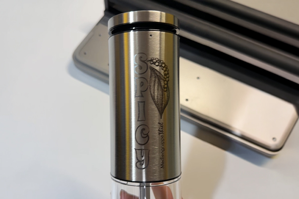 Faserlaser-Gravur: Gewürzmühle aus Edelstahl personalisieren Edelstahl-Gewürzmühle mit vertikaler „SPICY“-Gravur und Motiv, per Faserlaser dauerhaft markiert, fein kontrastiert.